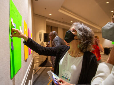 Judith Bell, San Francisco Team, places a post it note on a posterboard.